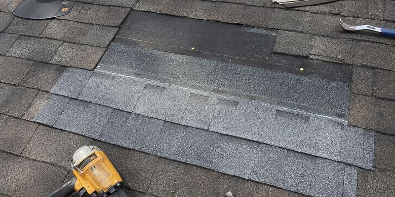 A roofer repairing asphalt shingles on a home in Milwaukee