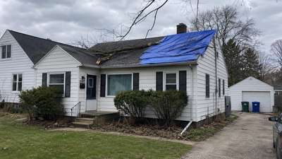 A Milwaukee home with a tarp covering storm damage from a fallen branch